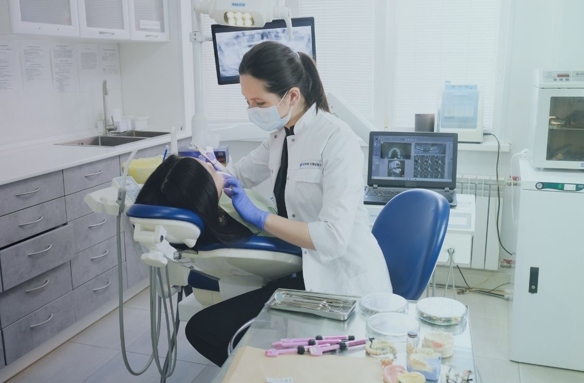 A dental assistant supports a dentist during a procedure in a modern dental office, illustrating the importance of skilled dental assistant recruiters in finding qualified talent for dental practices.