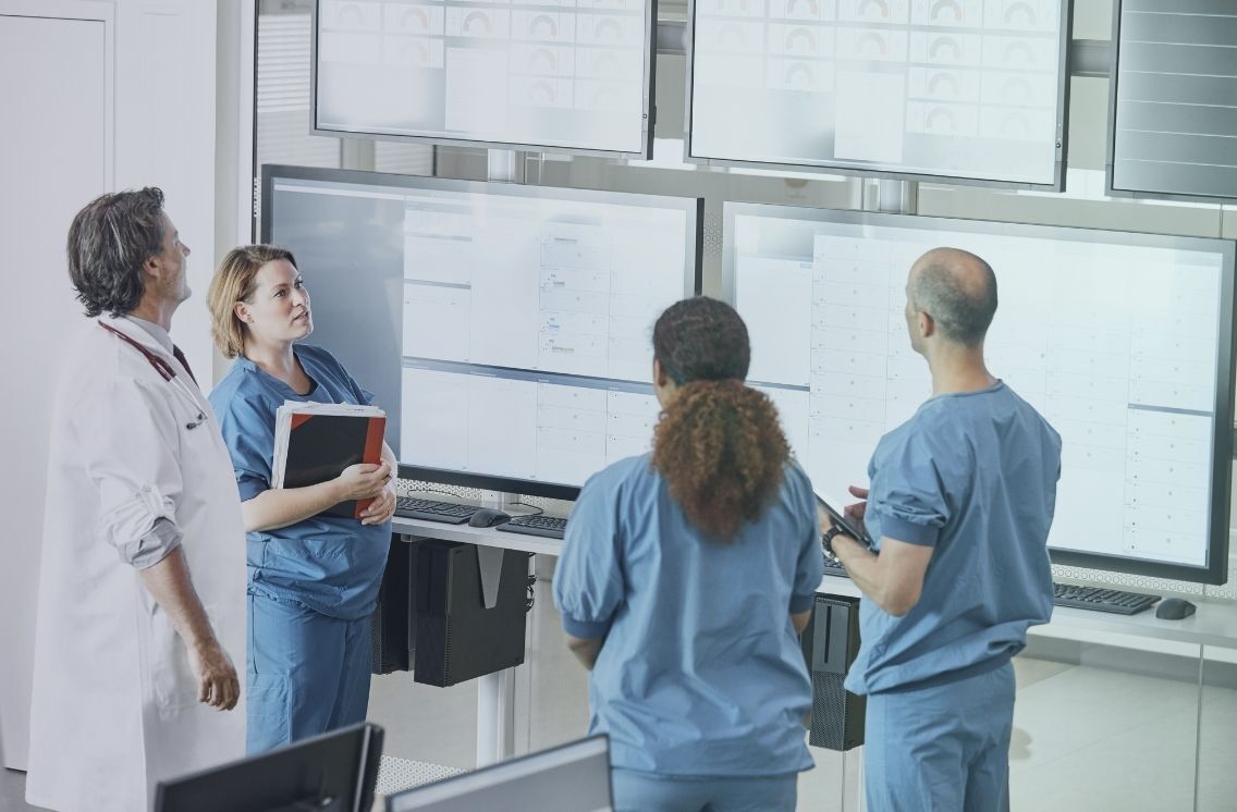 Medical recruitment team reviewing healthcare data on hospital screens.